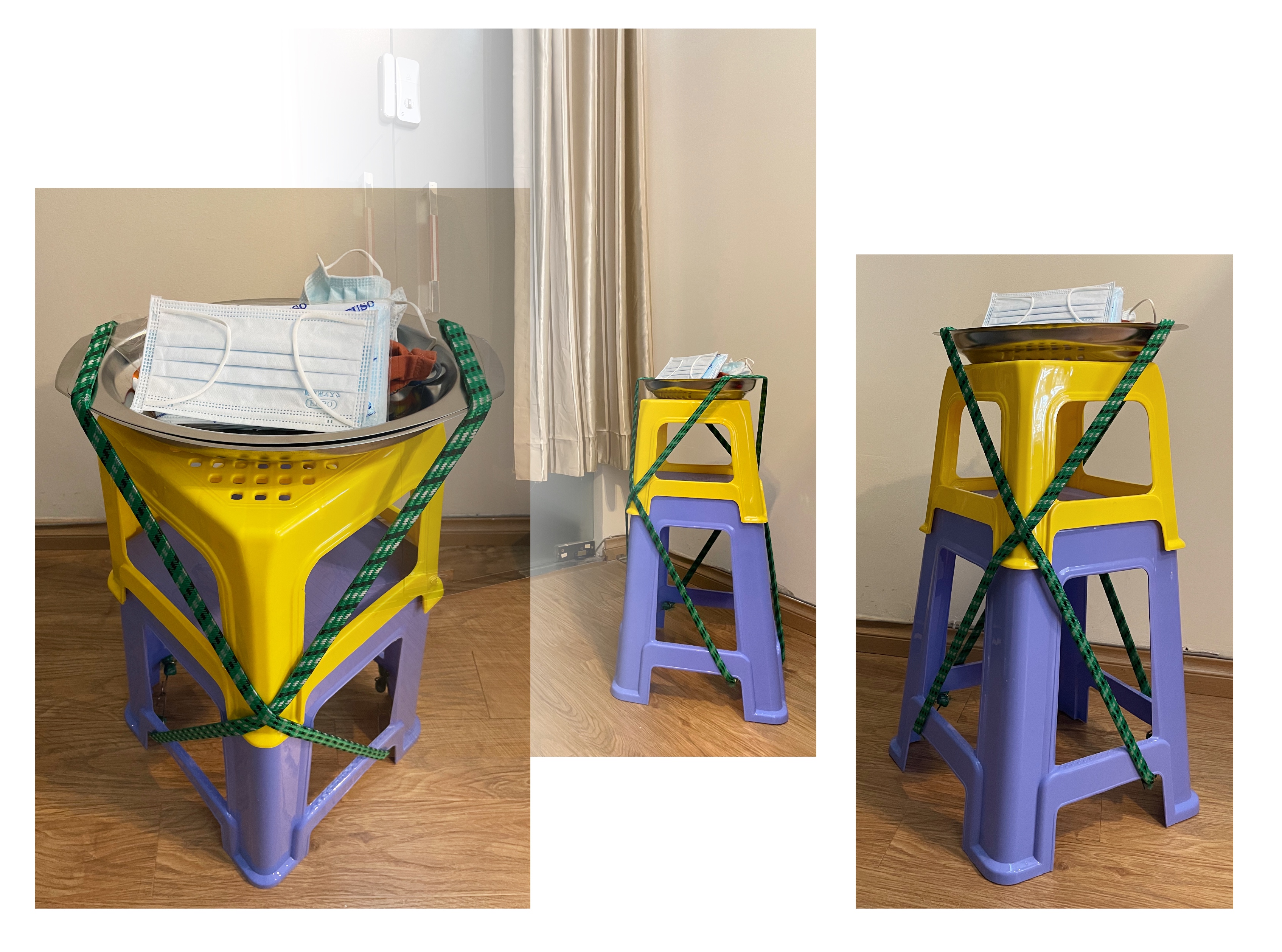 A pedastal-like structure. A blue stool of medium height is the base. A shorter yellow stool stands on it. A metal tray holding face masks is placed on top. The components are secured by two diagonally-placed green bungee cords. The structure is located near a door. The room is brown.